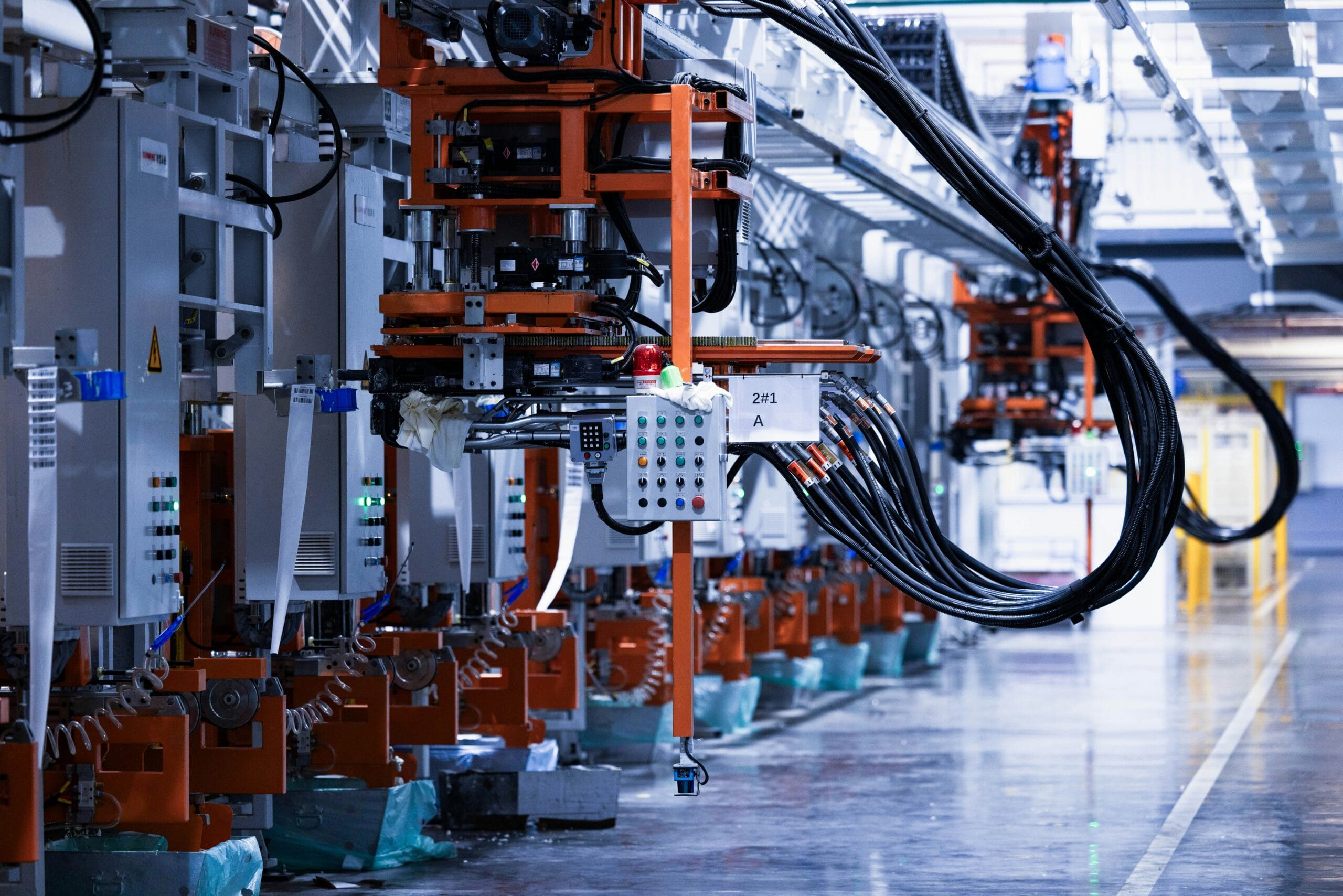 Automated machinery with robotic arms and numerous cables in a high-tech industrial setting.